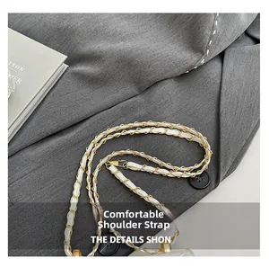 Close-up of golden metal chain interwoven with white leather on a trendy crossbody bag