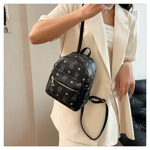 Close-up of black leather mini backpack with bear print and gold zipper on model