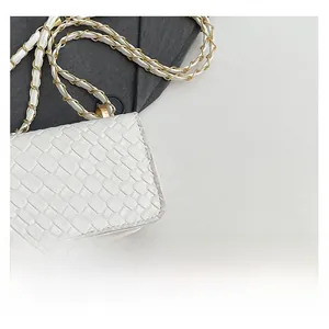 Macro detail of white woven crossbody bag with elegant gold chain shoulder strap