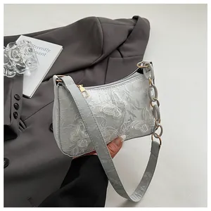 Detailed close-up of intricate butterfly and floral embroidery on a light gray handbag