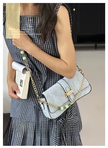 Détail du sac baguette bleu clair plissé avec boucle dorée et bandoulière en perles