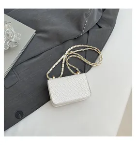 Detailed view of white woven texture and elegant gold-tone chain strap on crossbody bag