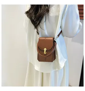 Detail of caramel brown mini bag showing woven texture and gold twist lock on white shirt