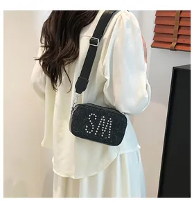 Close-up of black sequin camera bag featuring silver studded SM letter design