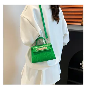 Mini sac à main vert vif gaufré croco porté avec une tenue blanche chic pour femmes
