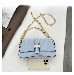 Détail du sac baguette bleu clair à texture marbrée avec fermoir H doré et chaîne