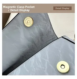 Gros plan détaillé du fermoir magnétique et de la texture plissée du sac baguette gris clair