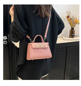 Détail d'un sac bandoulière rose embossé croco porté au dos par un mannequin