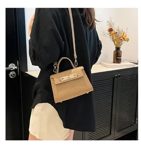 Sac à main élégant en crocodile kaki avec fermoir doré porté en bandoulière sur l'épaule.