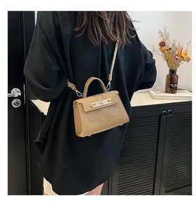 Détail d'un petit sac à bandoulière en texture crocodile beige avec fermoir doré.