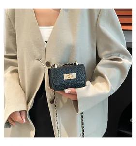 Detail of a mini black crossbody bag with woven texture and gold chain strap on a model