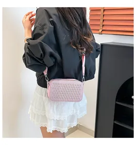 Rear view of model wearing pink crossbody camera bag with silver metallic studs