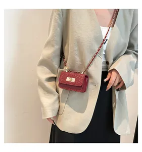 Detail view of burgundy woven crossbody bag with gold chain and twist lock closure