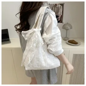 Dettaglio del ricamo in pizzo bianco e del grande fiocco decorativo sulla borsa tote