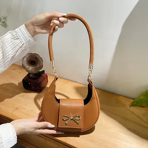 Dettaglio della borsa a mezzaluna marrone con fiocco in metallo dorato e trama in pelle