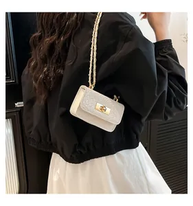 Detail of white woven mini crossbody bag with gold twist lock on person back view