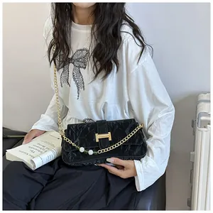 Gros plan d'un sac froncé noir avec boucle H dorée et bandoulière en perles et chaîne