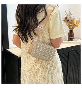 Detail of beige crossbody camera bag with silver stud embellishments and wide strap
