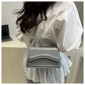 Sac bandoulière gris texturé avec rabat ondulé et boucle métallique en gros plan