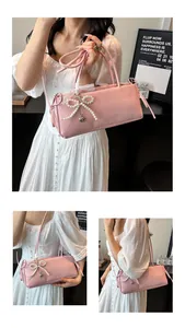 Detailansicht der rosa Schultertasche mit Perlenbogen und Herzanhänger an dem Model