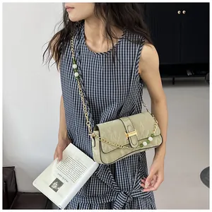 Détail d'un sac à main plissé vert clair avec chaîne dorée et bandoulière perlée