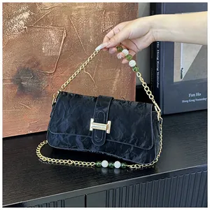 Détail du sac baguette noir plissé avec fermoir doré et bandoulière en perles colorées