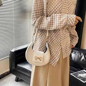 Dettaglio della borsa hobo bianca a mezzaluna con fibbia a fiocco dorato decorativo