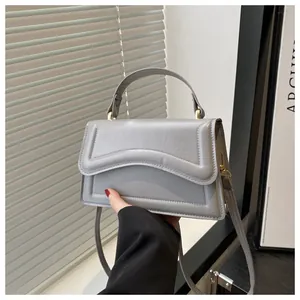 Détail du sac à main gris clair avec rabat gaufré ondulé et finitions en métal doré