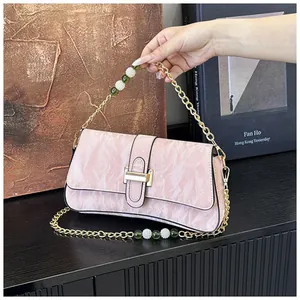Détail du sac baguette rose avec bandoulière chaîne dorée, perles et perles vertes décoratives
