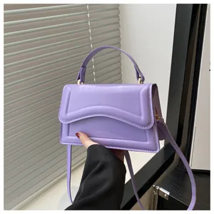 Détail du sac à main violet clair avec rabat gaufré à vagues et ferrures dorées chic