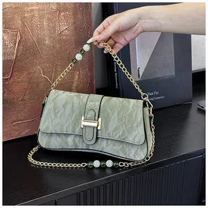 Détail du sac baguette vert clair avec chaîne perlée et boucle métallique dorée