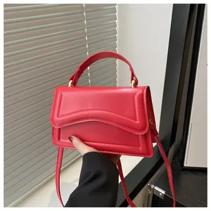 Détail du sac carré rouge avec similicuir matelassé à vagues et garnitures dorées