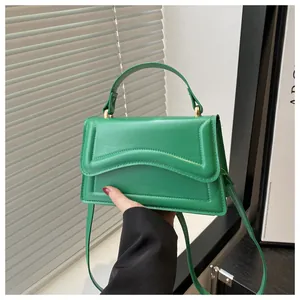 Détail du sac à main vert en similicuir avec rabat à motif ondulé et pièces métalliques