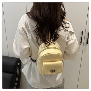 Quilted beige mini backpack with silver twist lock shown on model from a back view