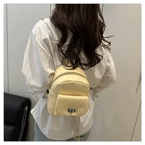 Detail of cream quilted mini backpack featuring silver twist lock and chain strap