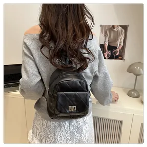 Detail shot of black quilted mini backpack with silver chain straps worn by model