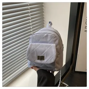 Close-up of light blue quilted backpack featuring silver twist lock and chain strap detail