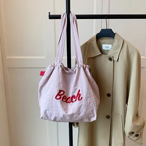 Pink nylon drawstring tote bag featuring red Beach embroidery and long shoulder straps