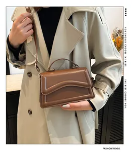 Close-up of brown wavy flap handbag featuring a gold hardware clasp and sleek top handle