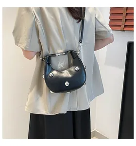 Détail du sac croissant noir avec clous sphériques argentés et fine bandoulière en cuir