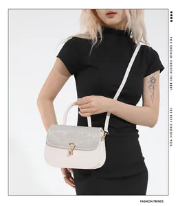 Detail van beige crossbodytas met pailletten flap en een gouden hoefijzervormige gesp