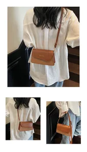 Close-up van bruine crossbodytas met gouden Fashion and Bags logo op de voorste klep