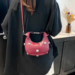 Sac bandoulière demi-lune en cuir bordeaux avec des clous métalliques argentés