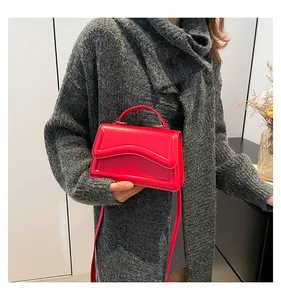 Detail of red leather crossbody bag with wave design and model in knitwear sweater