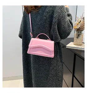 Detail of pink PU leather handbag with wavy quilting and adjustable strap worn by model