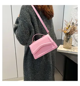 Detail of pink glossy patent leather handbag with wavy embossed patterns on the flap