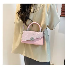 Détail montrant les paillettes roses et le fermoir en forme de cœur de ce sac à main