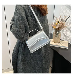 Close-up of a silver metallic crossbody bag featuring wavy embossed patterns and top handle
