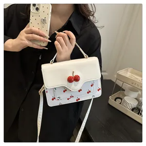 Detail of cute cherry print crossbody bag with 3D cherry decor on the white flap