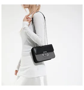 Detail of elegant chain strap and luxury lock on a black and grey small square bag
